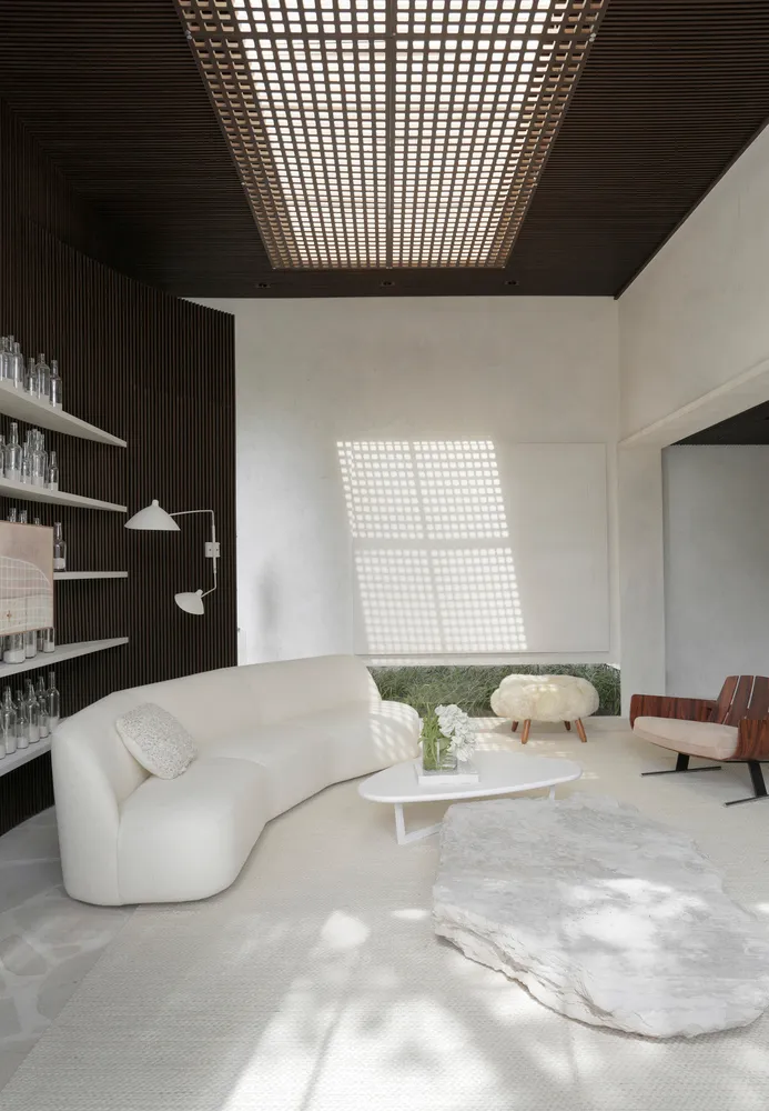 A contemporary living room featuring a sleek, white leather sofa against a minimalist backdrop with a white, textured rug and