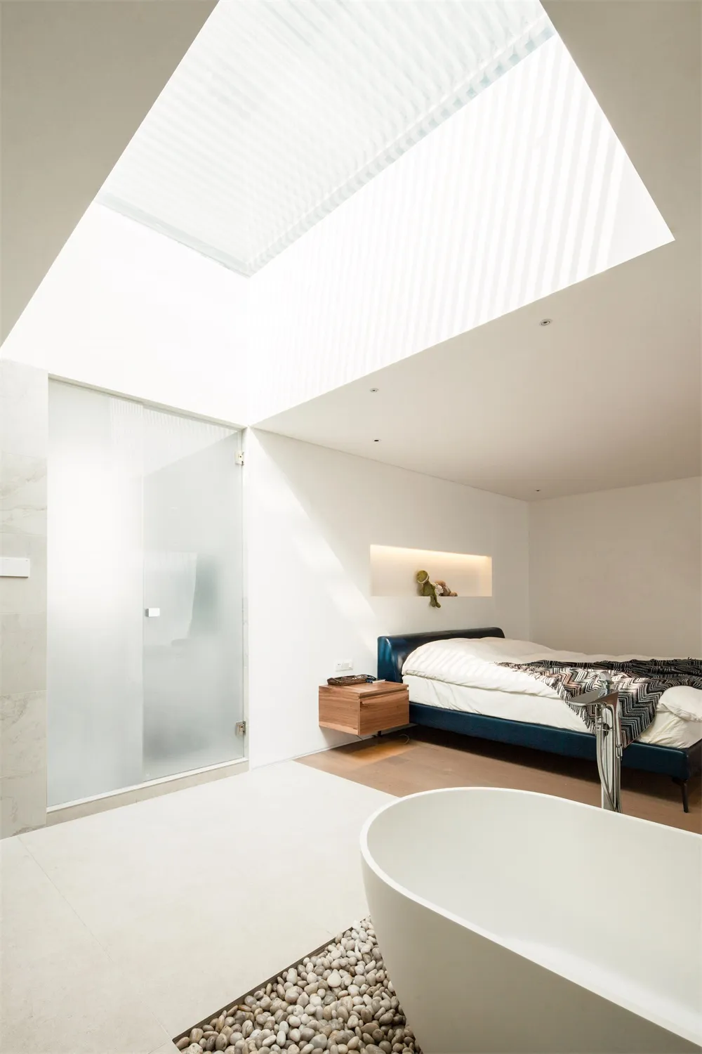Modern minimalist bedroom featuring a concrete floor and large glass window.