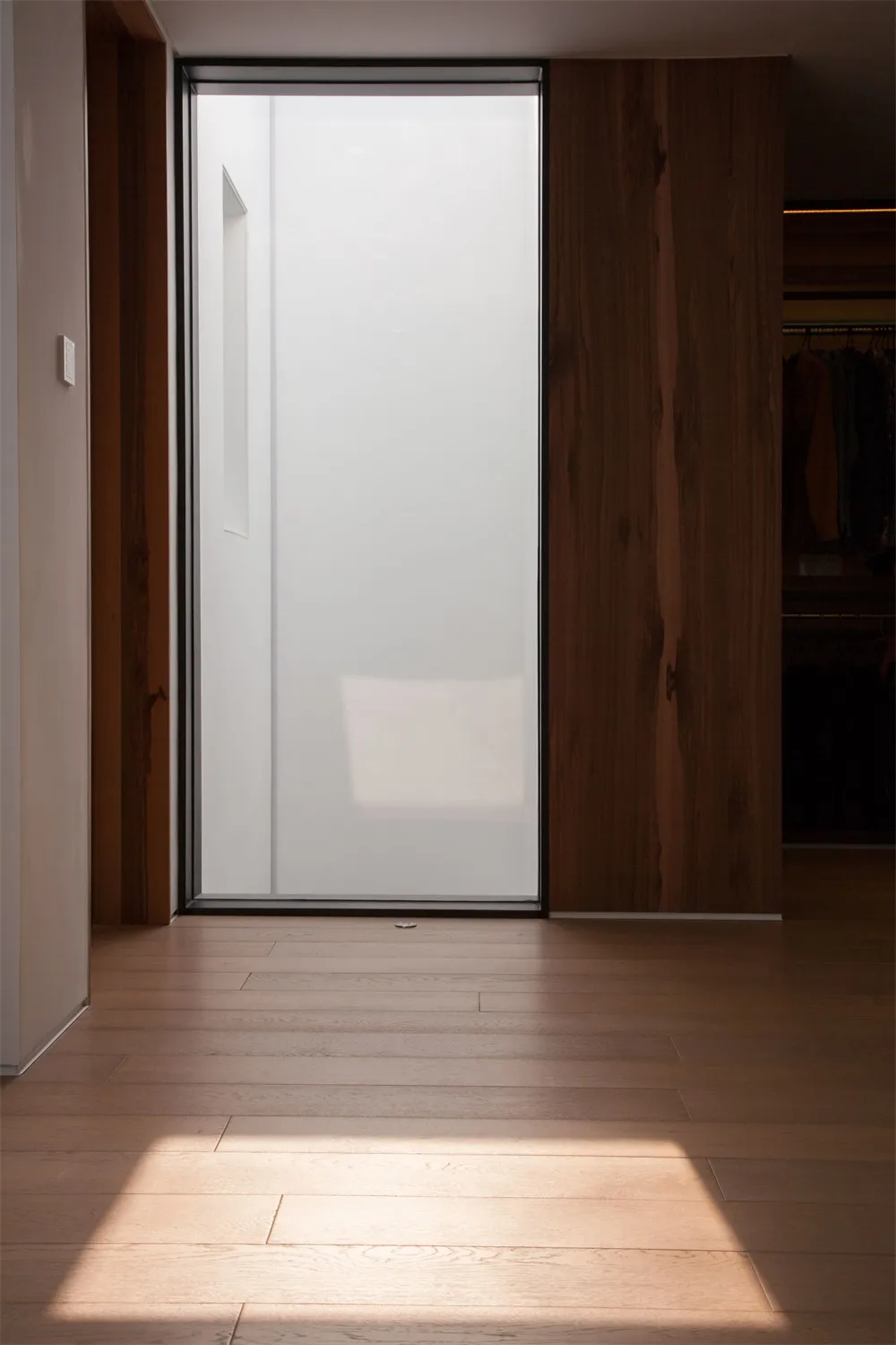 Minimalist interior design featuring a frosted glass wall and wooden floor.