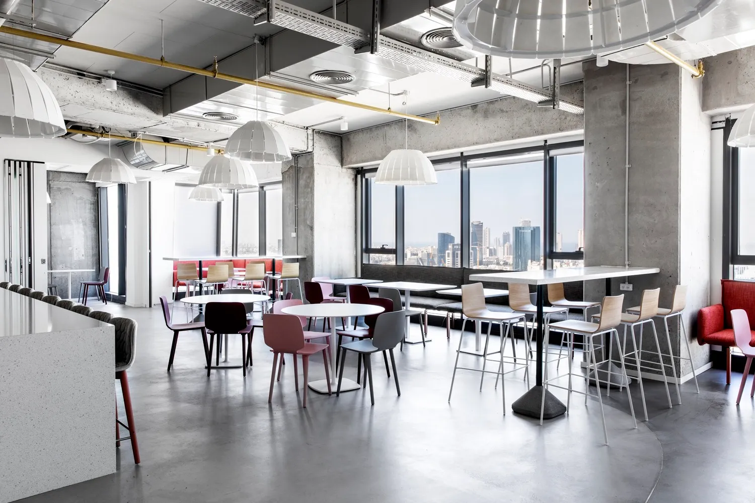 A modern office cafe featuring concrete walls and glass partitions.