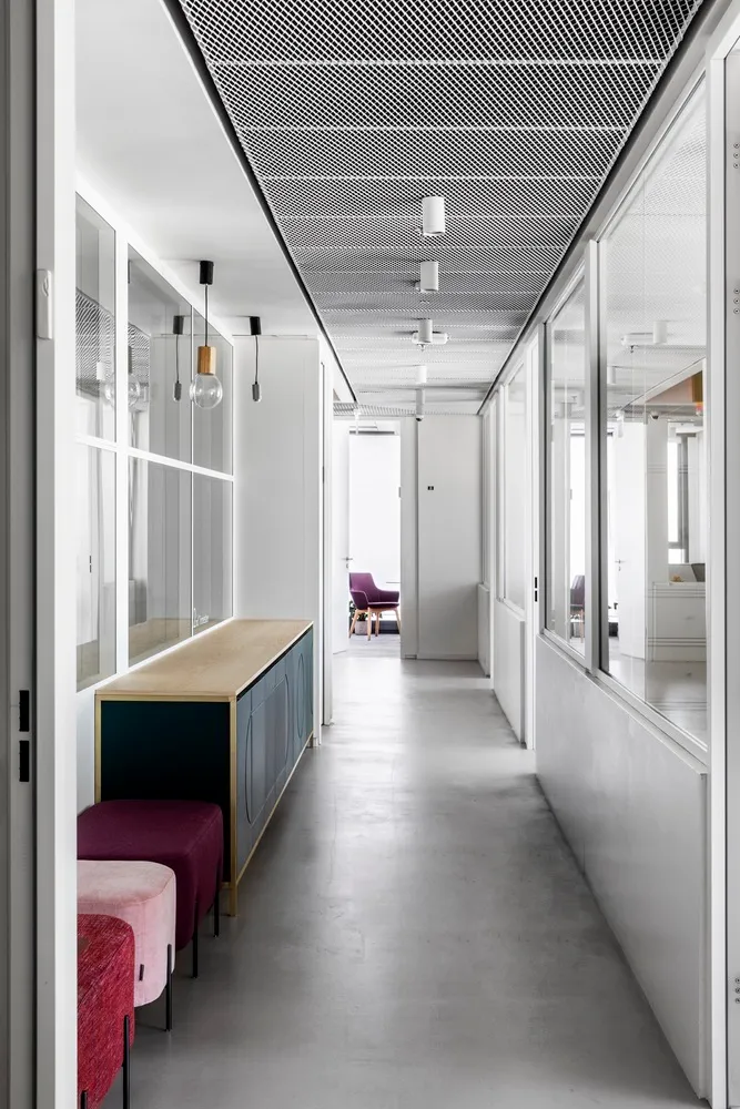A minimalist office with concrete flooring, glass partitions, and modern furniture.