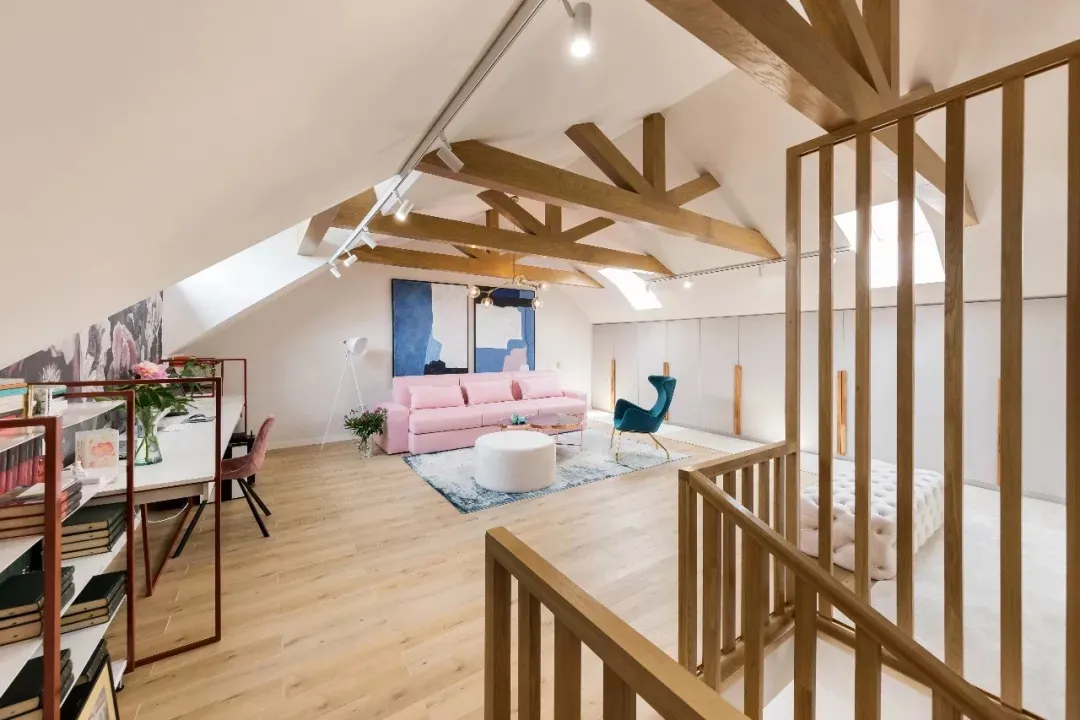 A modern living room featuring a pink sofa, wooden beams, and a blue and white abstract painting.