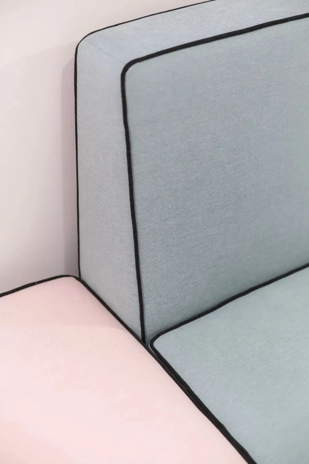 Modern light blue and pink upholstered sofa with contrasting black piping.