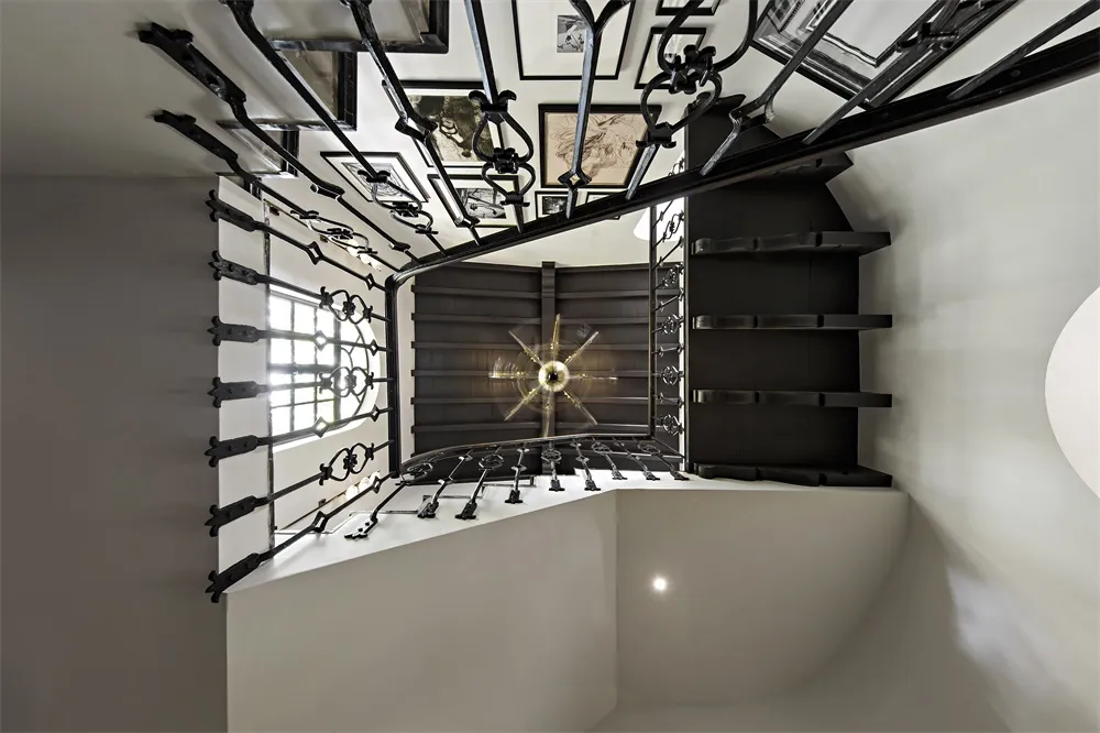 A black metal staircase with intricate railings leading to a white interior space.