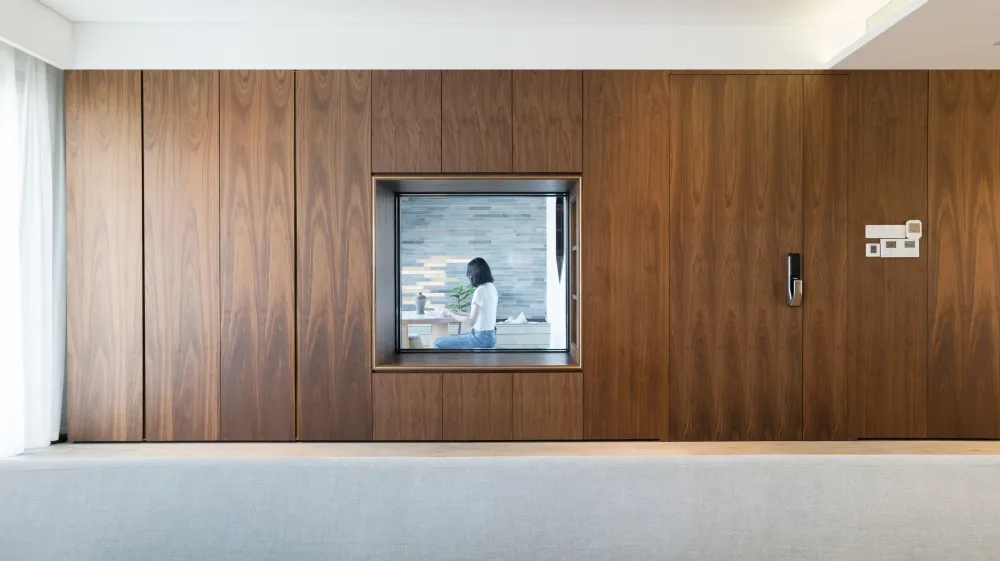 A minimalist window seat is framed by natural wood paneling, offering a cozy spot for relaxation and observation within a cle