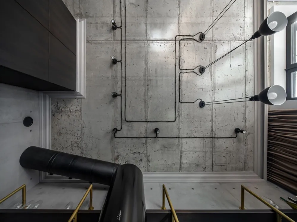 A modern industrial interior design featuring a concrete wall with exposed wiring and black cylindrical elements.