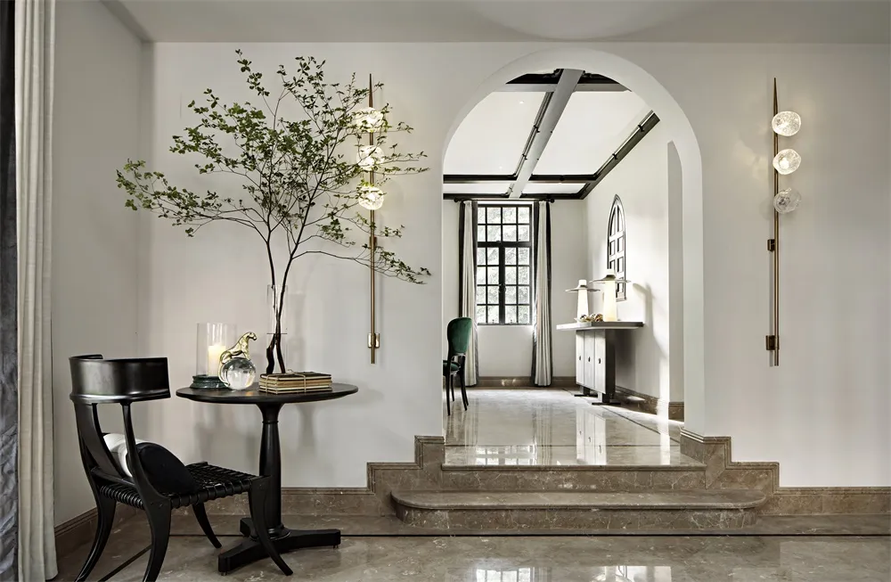 A minimalist living room featuring marble floors and a modern arched doorway.