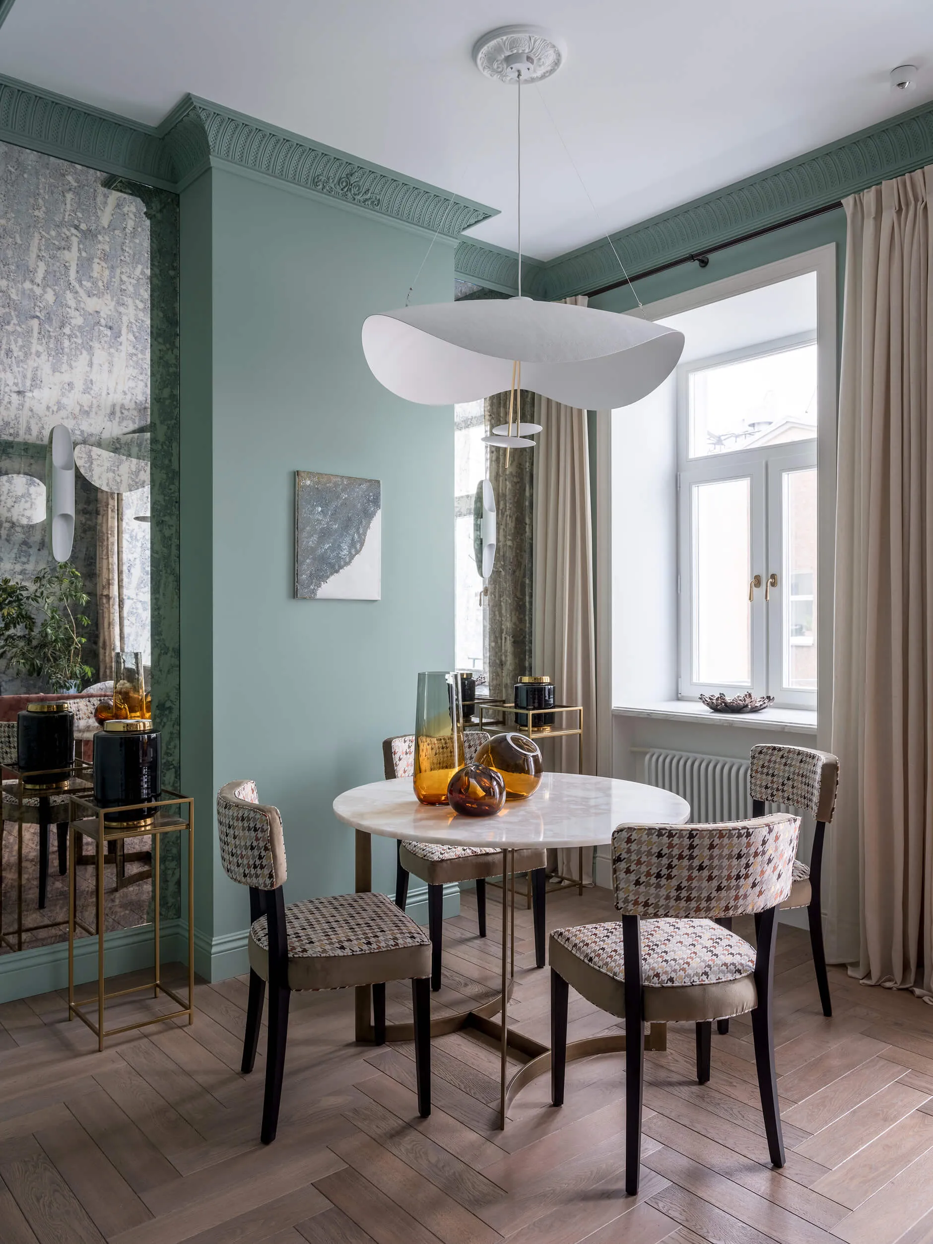 A modern dining room with a round marble table and upholstered chairs featuring a geometric pattern.