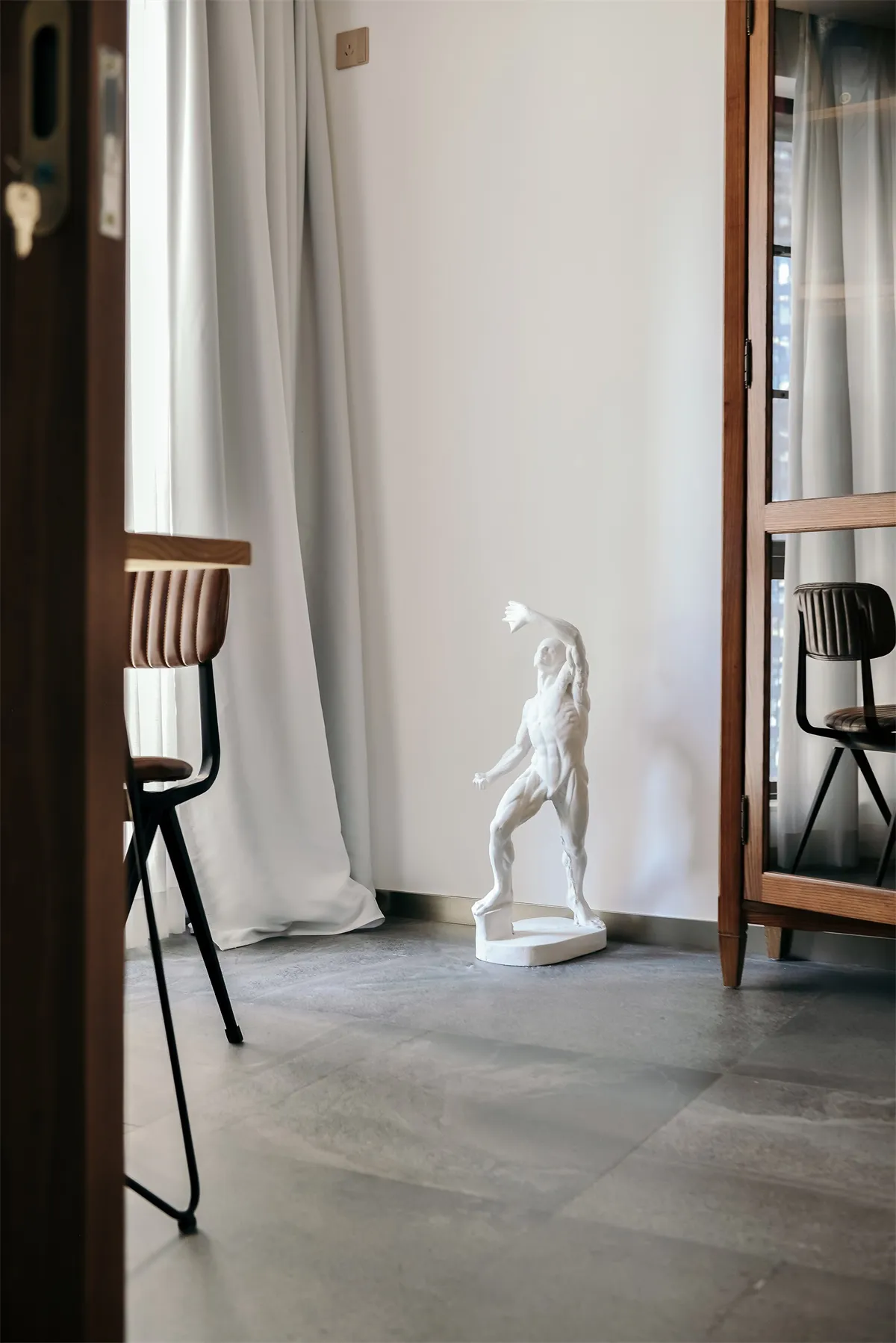 A modern concrete living room with minimalist furniture and a sculptural white statue.