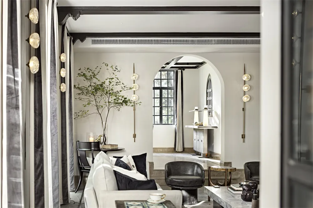 A modern living room featuring a white leather couch, a coffee table with a white bowl, and decorative sconces on the walls.