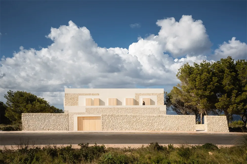 A modern residential building with stone and plaster exterior in a natural setting.