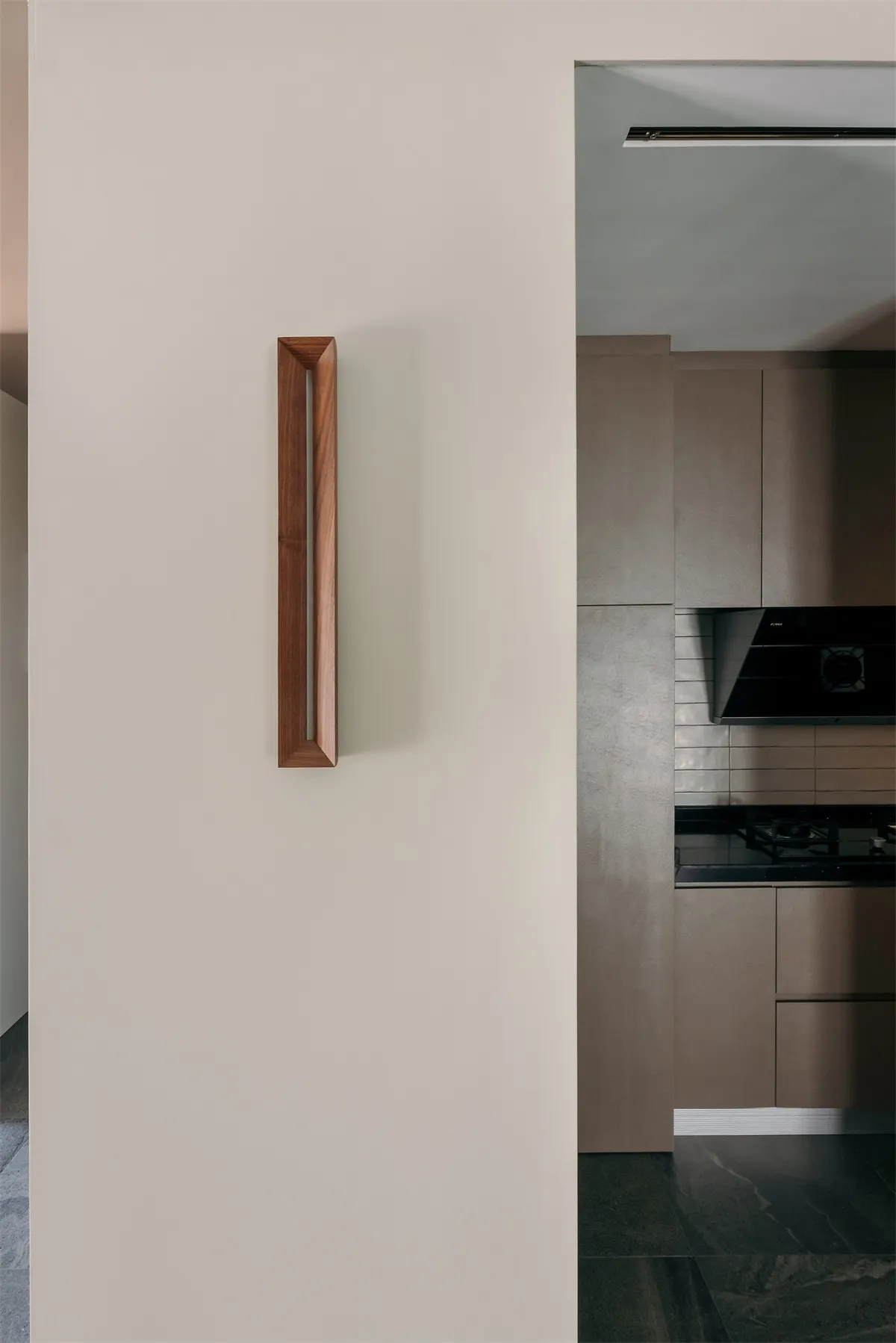 A modern kitchen interior featuring a wooden handle on a door or cabinet.