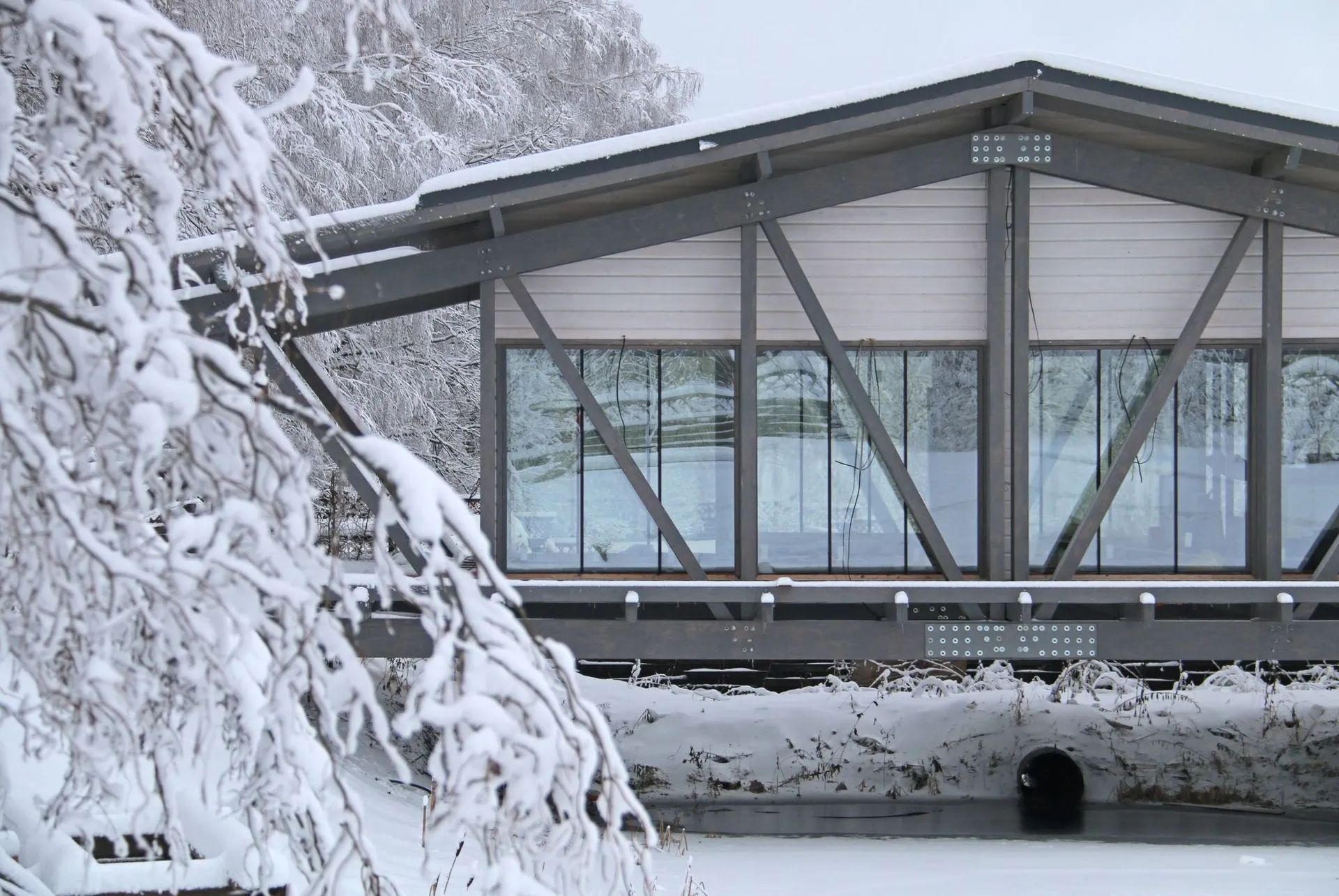 一座金屬住宅橋，搭配玻璃面板，橫跨雪景之上。