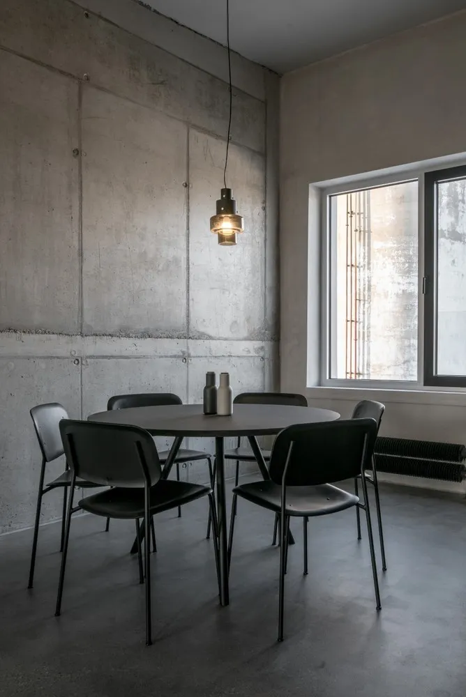 An industrial-designed dining room featuring concrete walls and flooring.