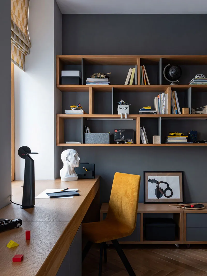 A modern home office with a wooden desk and shelves.