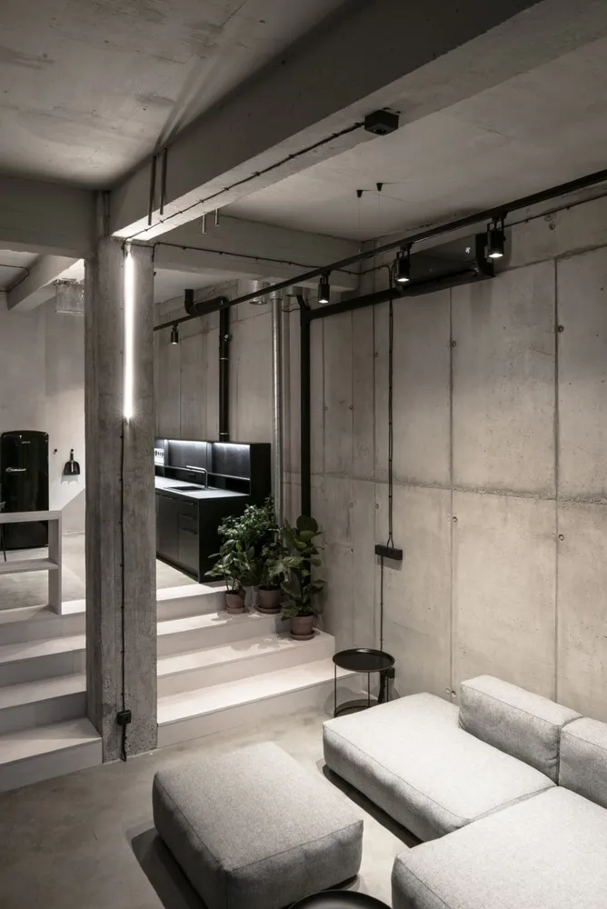 An industrial-style modern living room with concrete walls and black accents.