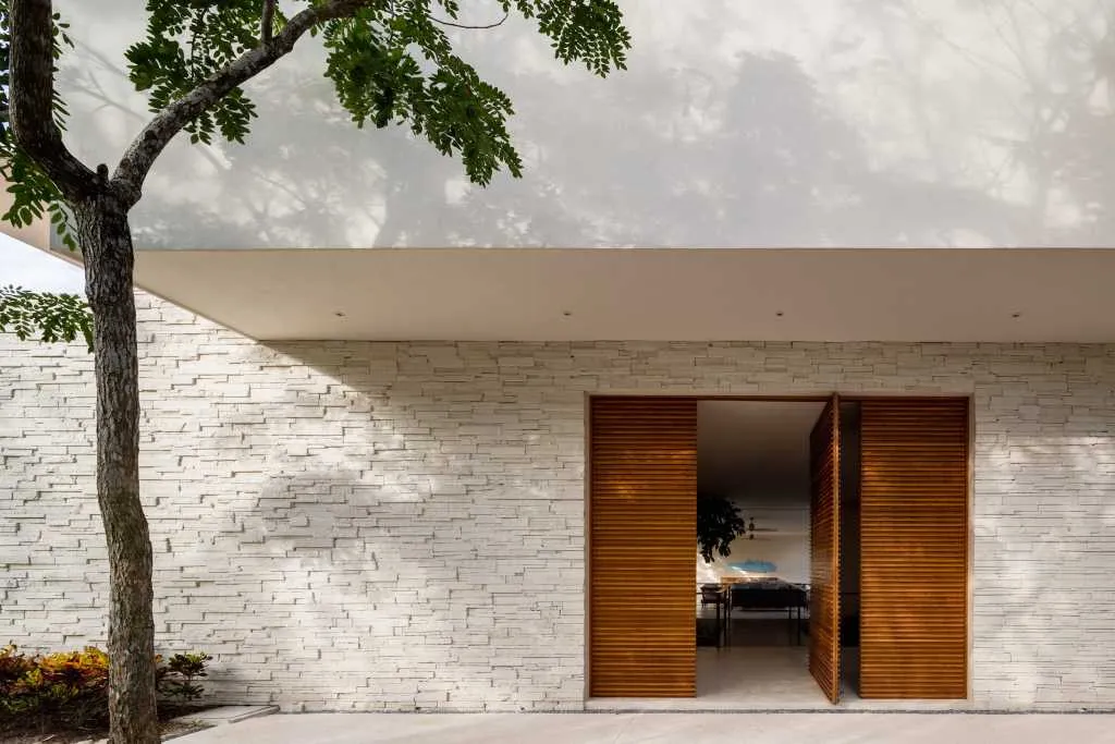 A modern residence featuring a textured brick facade and a large wooden door.