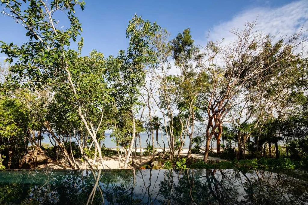 A serene beach retreat with natural elements and a calm pool.