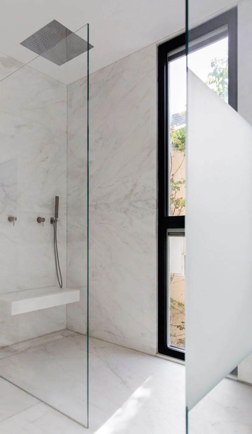 Modern minimalist bathroom with white marble walls and floor.