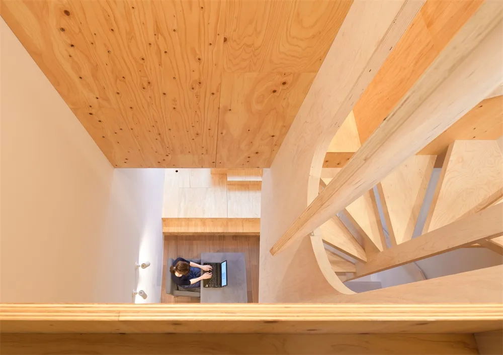 Minimalist interior space featuring wood elements and a spiral staircase