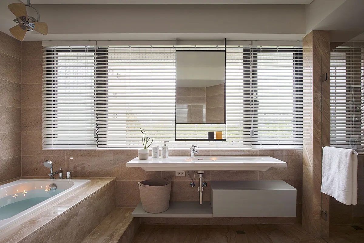 Modern bathroom with concrete walls, a white floating sink, and blinds on the window.