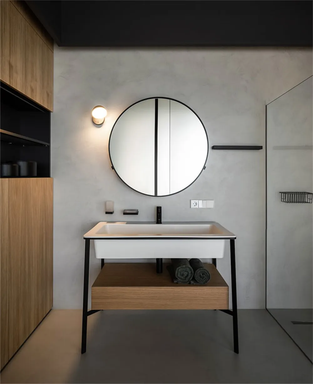 Modern minimalist bathroom featuring a white sink with a black faucet, wooden shelves, and a round mirror.