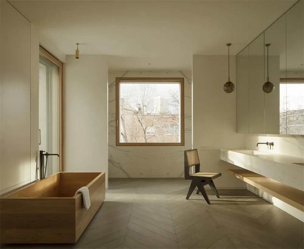 Modern minimalist bathroom featuring a wooden bathtub and marble walls.