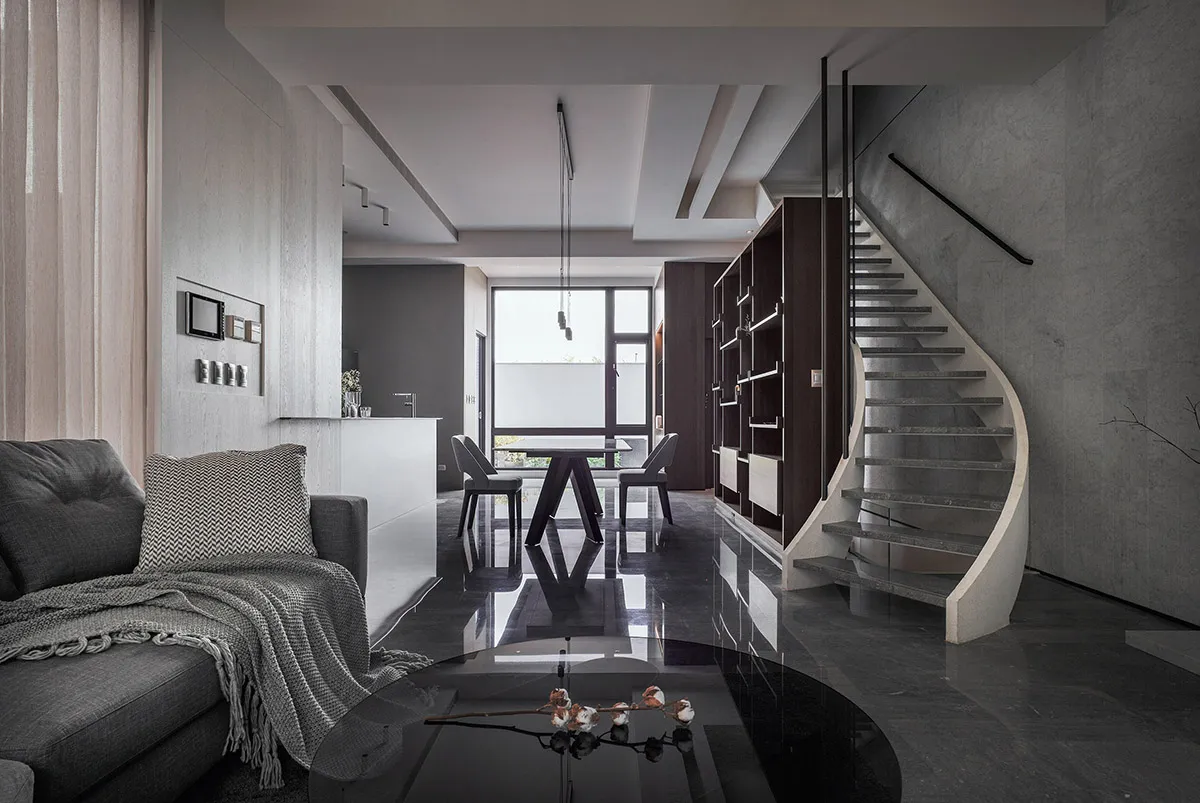 A stylish modern interior featuring a black concrete floor, metal accents, and a sleek furniture arrangement including a larg