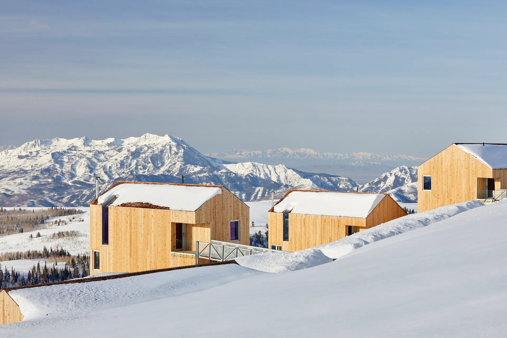 現代極簡住宅覆蓋在雪中,背景為山巒。