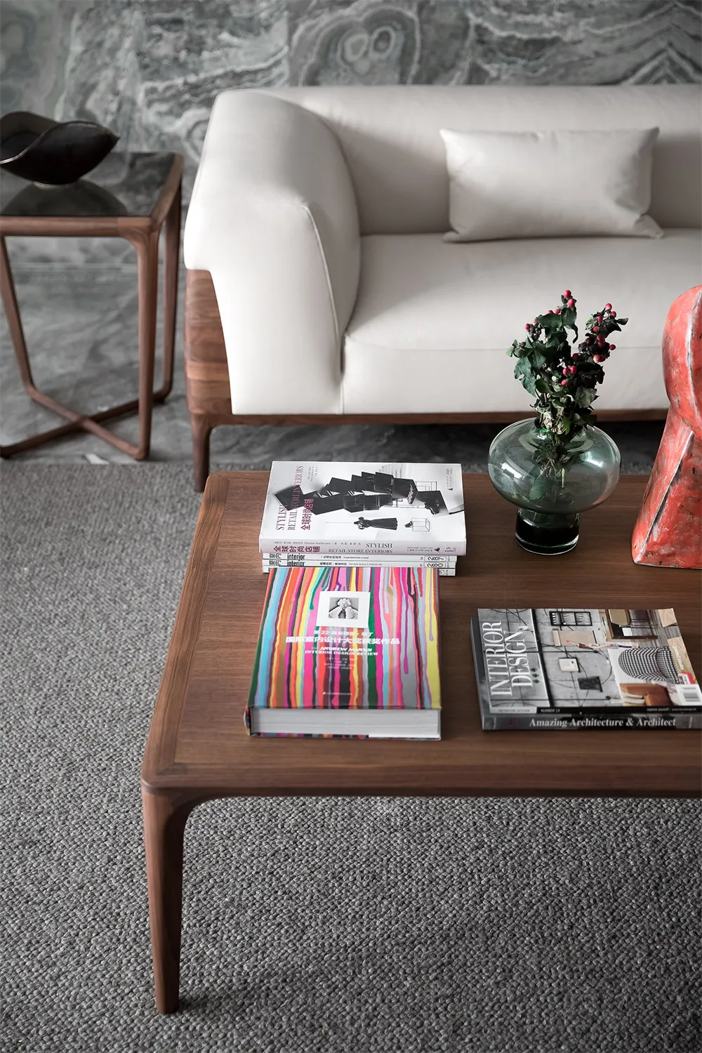 A modern coffee table with a colorful striped centerpiece, a vase with greenery, and several books.