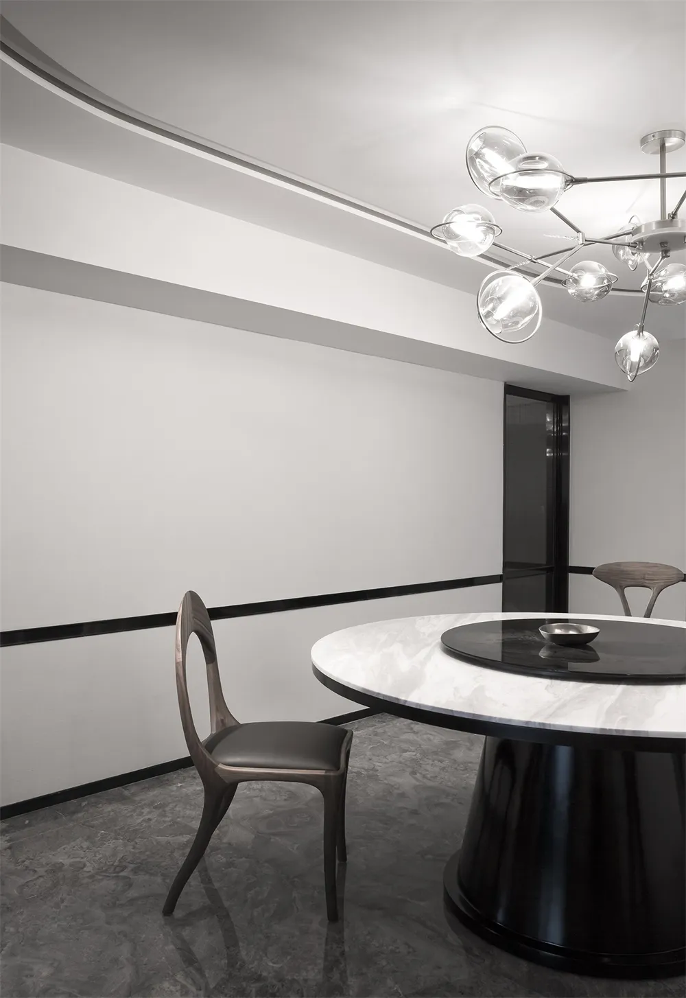 A modern minimalist dining room featuring a round marble table and black-and-white color scheme.