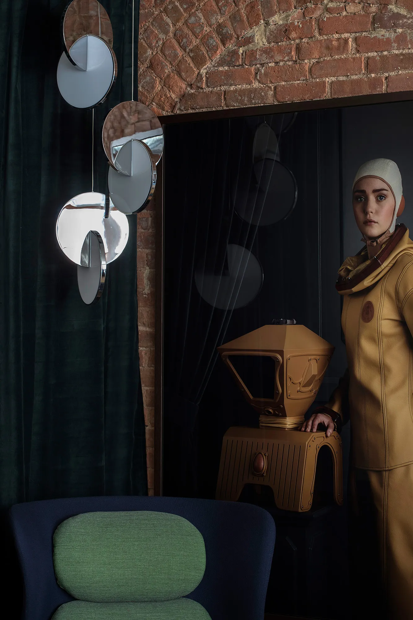 A futuristic laboratory scene featuring a metallic sculpture and modern furniture against a brick wall.