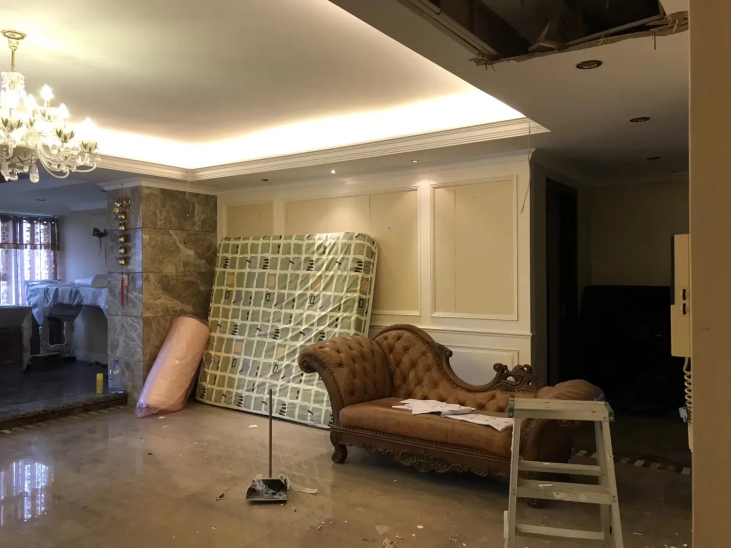 客廳內有混凝土地板、大理石柱，以及翻修工具。