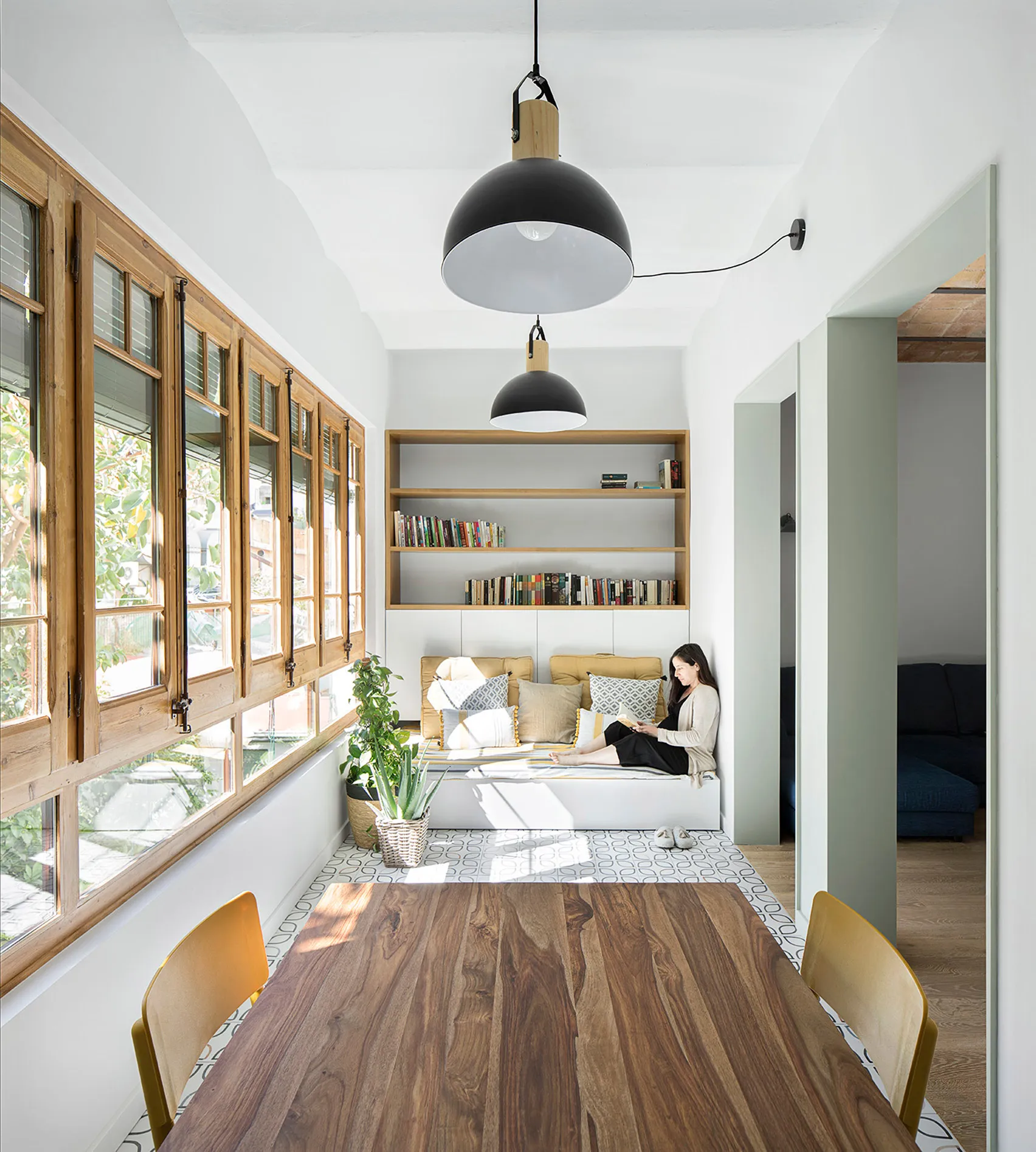 A minimalist dining room with wooden flooring, furniture, and shelves.