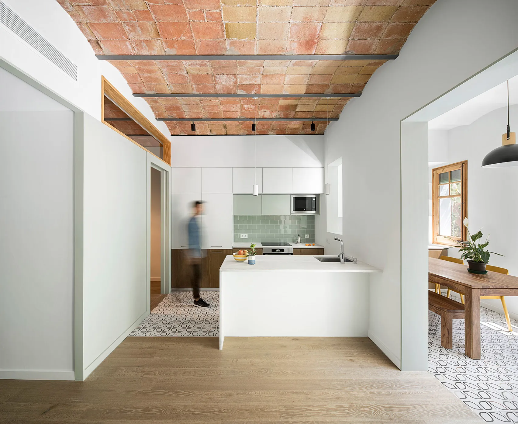 A minimalist kitchen with white cabinets, a central island, and a tile floor.