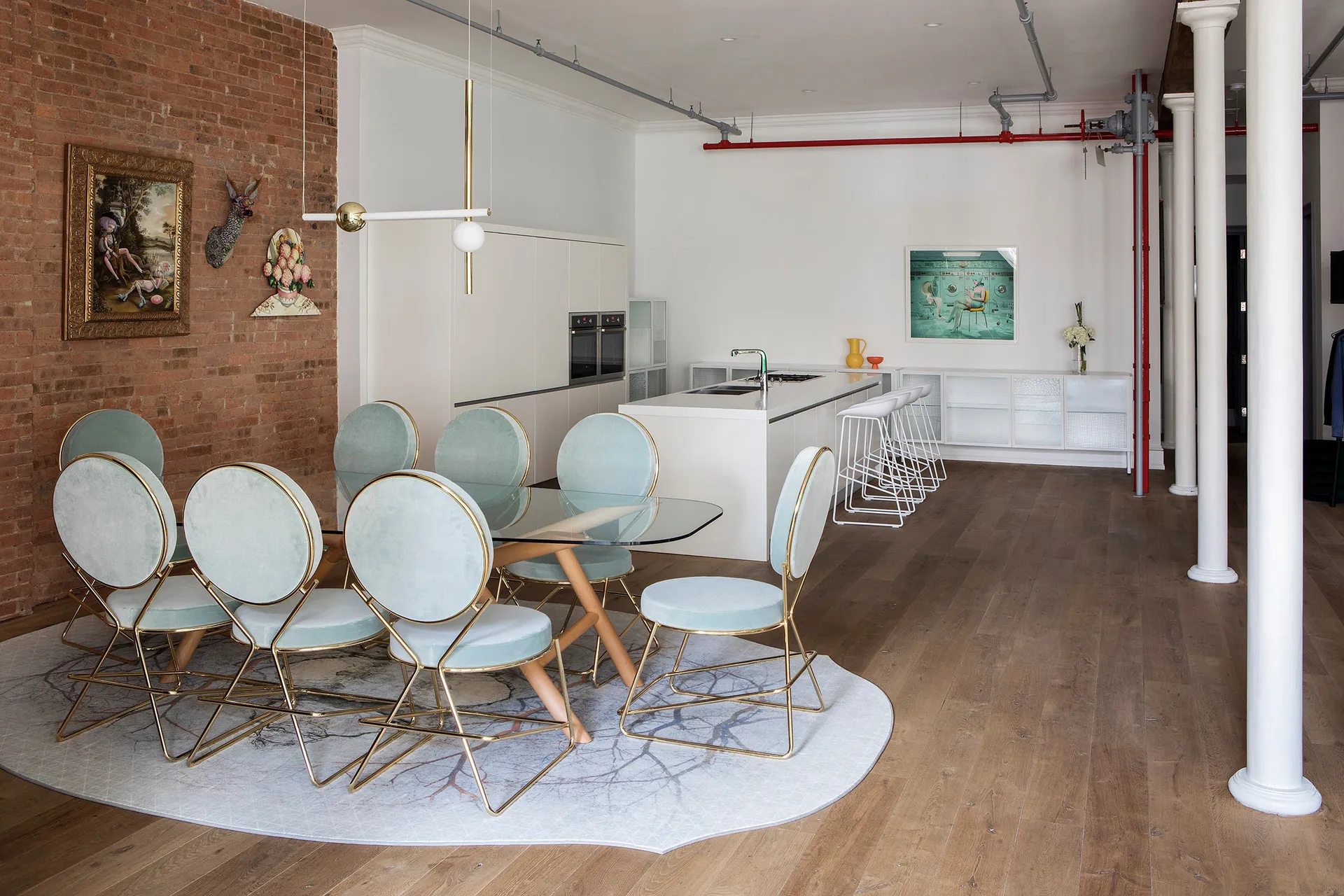 Modern residential space featuring a dining table with blue upholstered chairs and metal framing, a kitchen island, and a bri