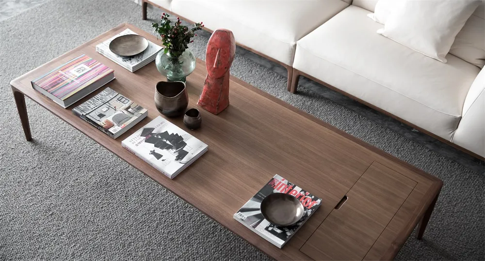 Modern living room featuring wooden furniture, including a low wooden coffee table with books, magazines, and decorative item