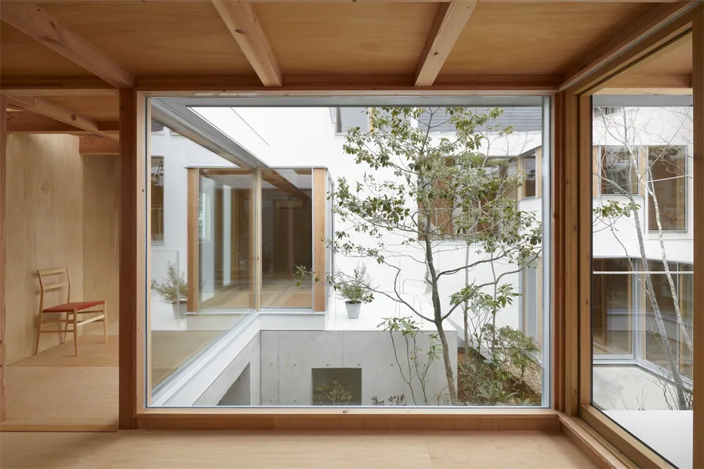 A minimalist interior design showcases a natural wooden floor and ceiling, with large windows allowing natural light to enter
