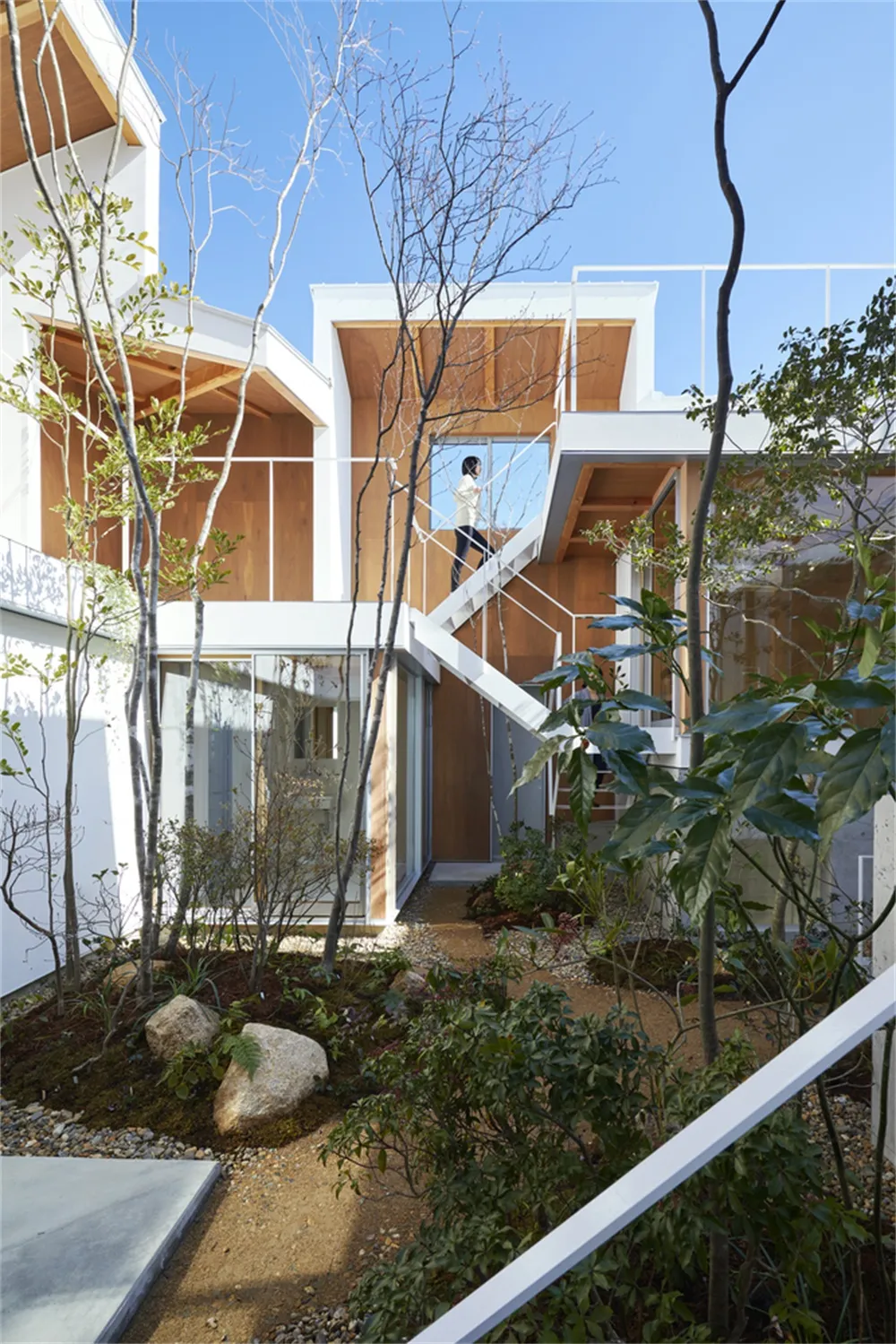 Modern residential building with white exterior, concrete walls, glass windows, and wooden accents.