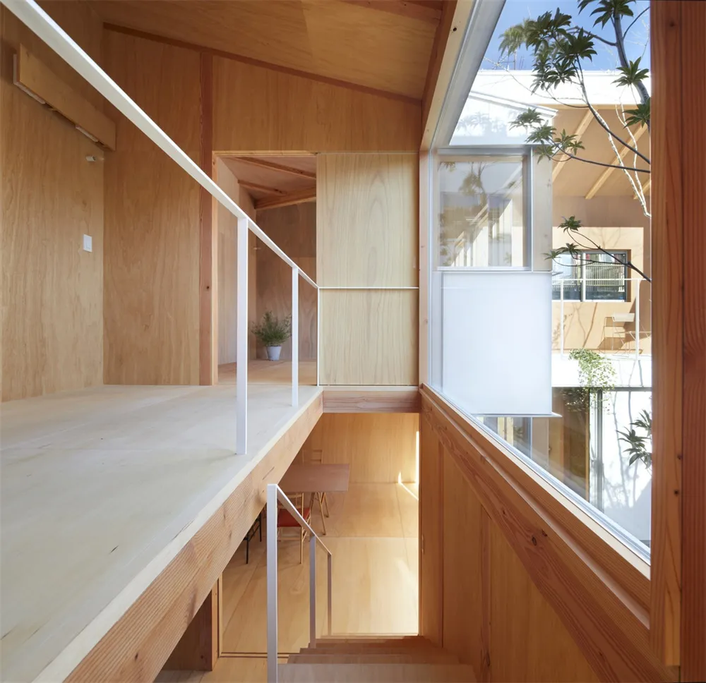 Modern wooden home interior with a staircase and large windows.