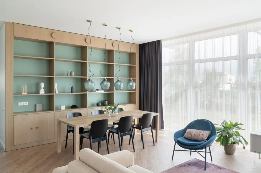 Modern living room with wooden shelving, black chairs, and a blue armchair.