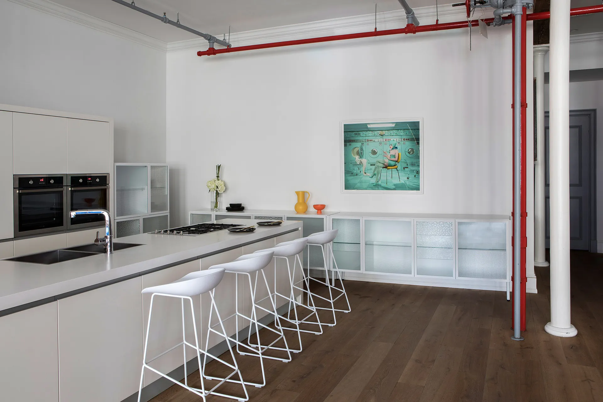 Modern minimalist kitchen featuring sleek white cabinets, a clean white countertop, and a white industrial-style bar with sto