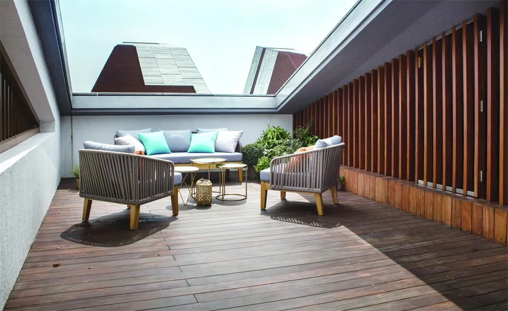 Modern rooftop patio featuring a comfortable seating area with wooden flooring and green plants.
