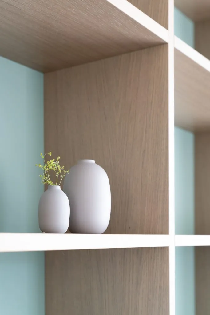 Two minimalist ceramic vases on a wooden shelf.