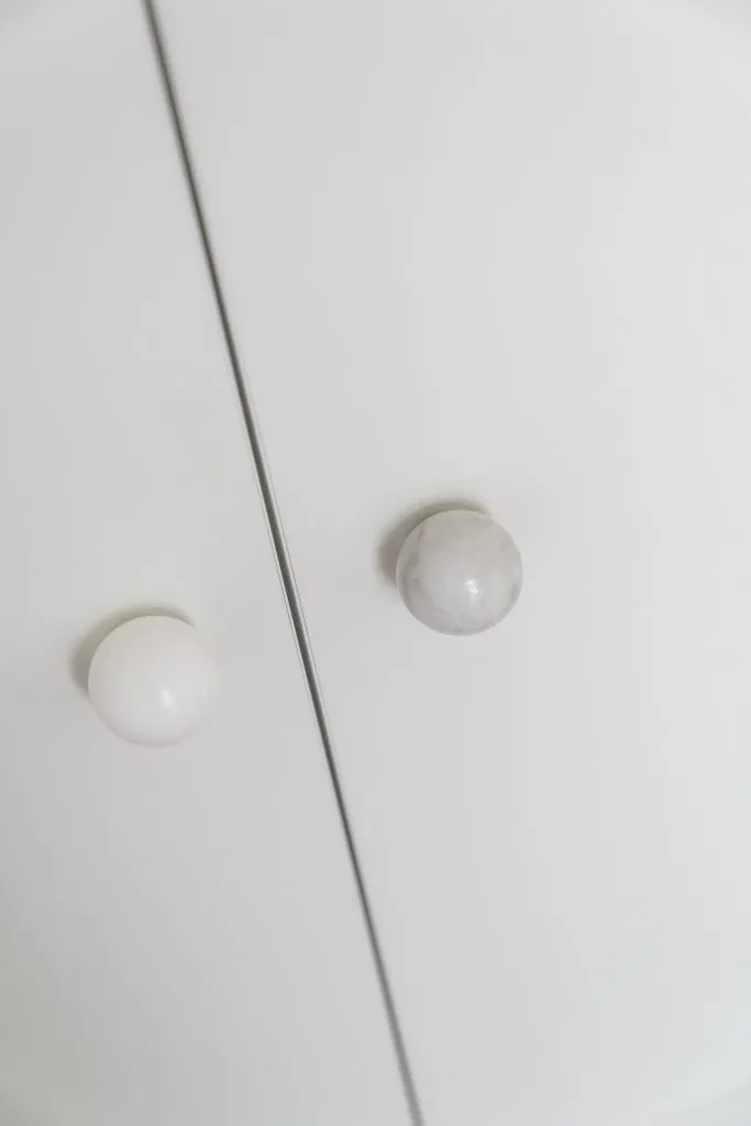 A white and marble door knob against a white background