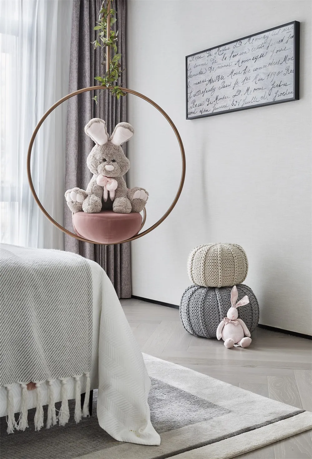 A minimalist child's bedroom with a white bed, gray curtains, and a hanging pink cushion for a rabbit plush toy.