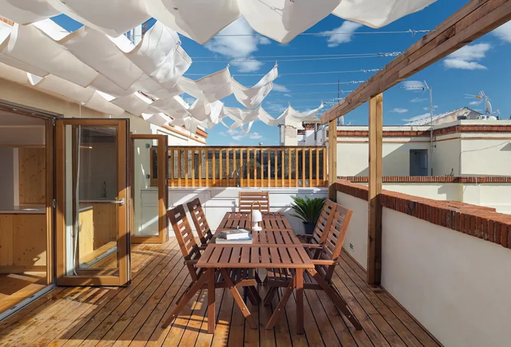 Modern balcony featuring wooden terrace under a canopy of white fabric.