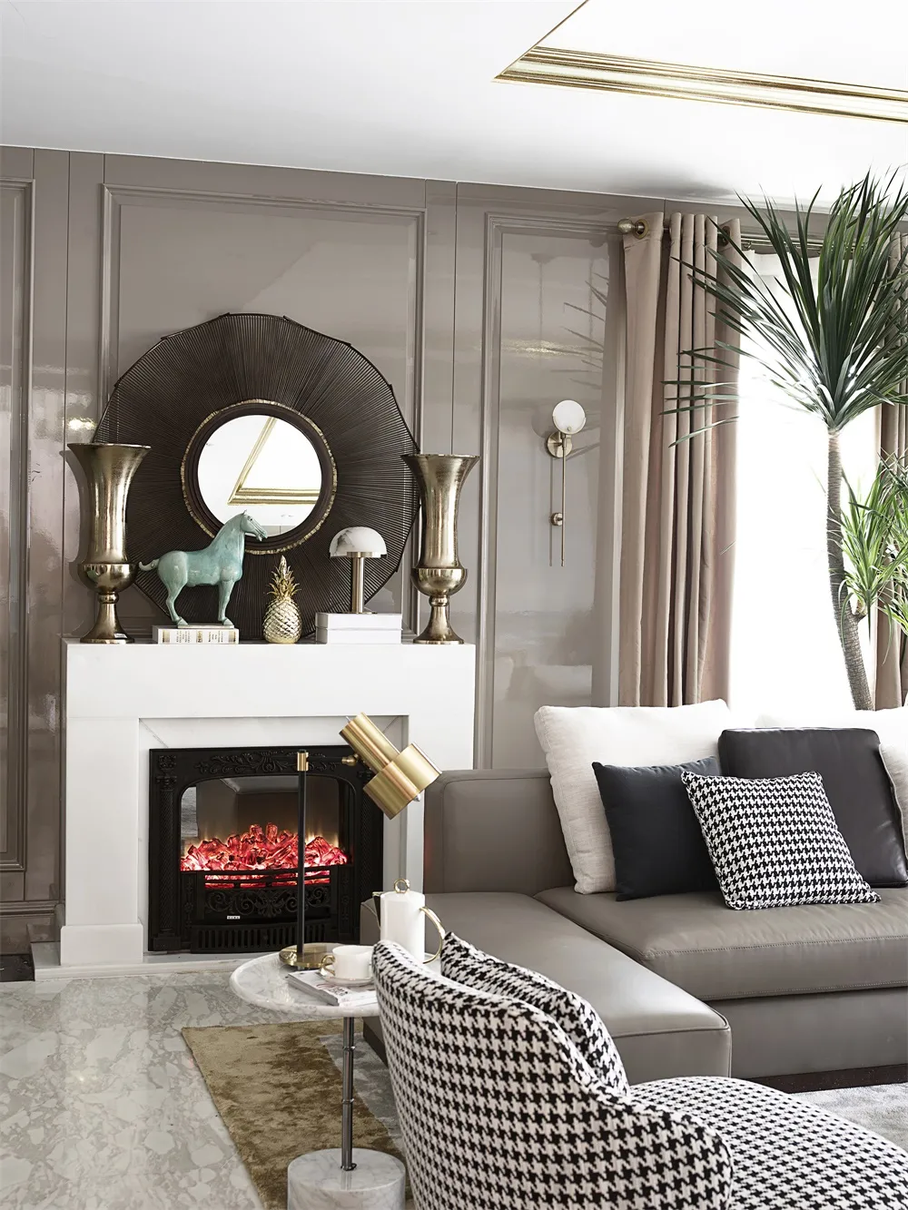 A modern living room with taupe-colored walls and a fireplace, featuring a corner sofa, decorative vases, and a large mirror.