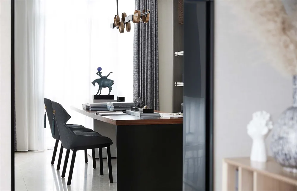 A modern office space featuring a sleek desk with stacks of books, chairs, and a decorative horse statue on a desk.