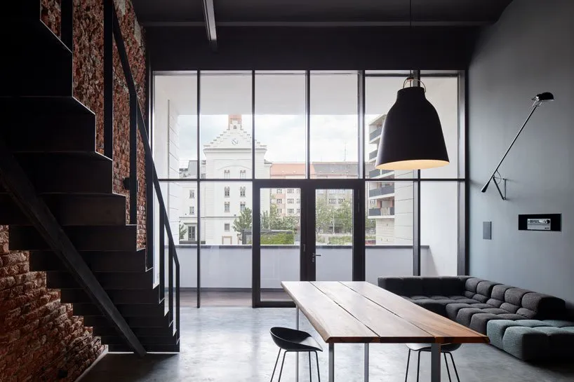 A spacious industrial living room with concrete and wooden furniture.